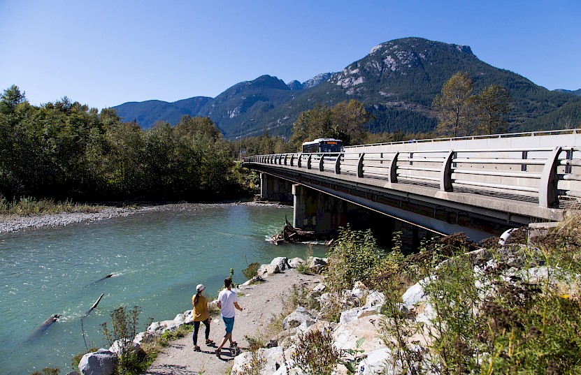 Squamish transit bus crosses the Mamquam River bridge with walkers on a lower trail